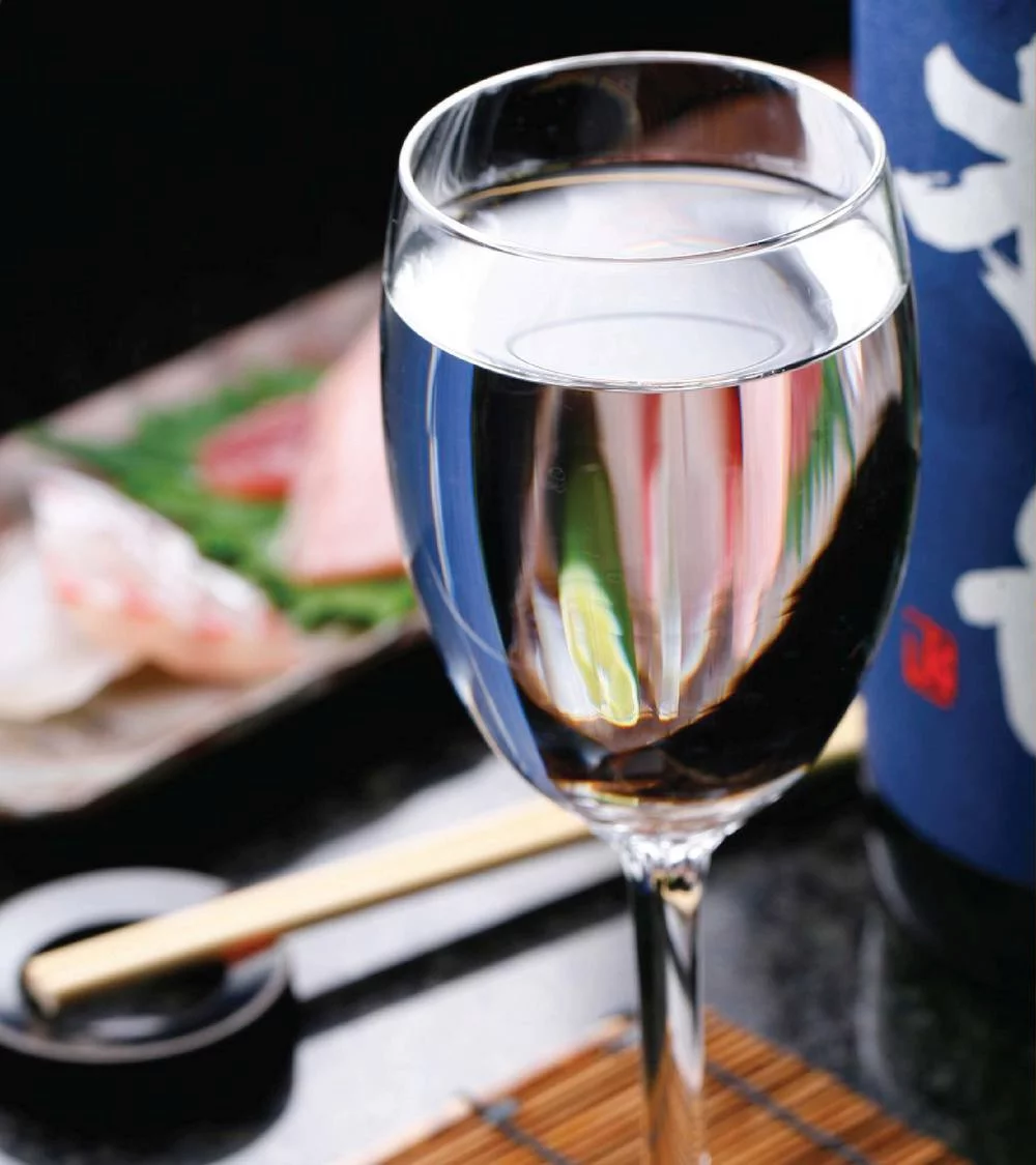 Clear sake in glass with Japanese dining background.